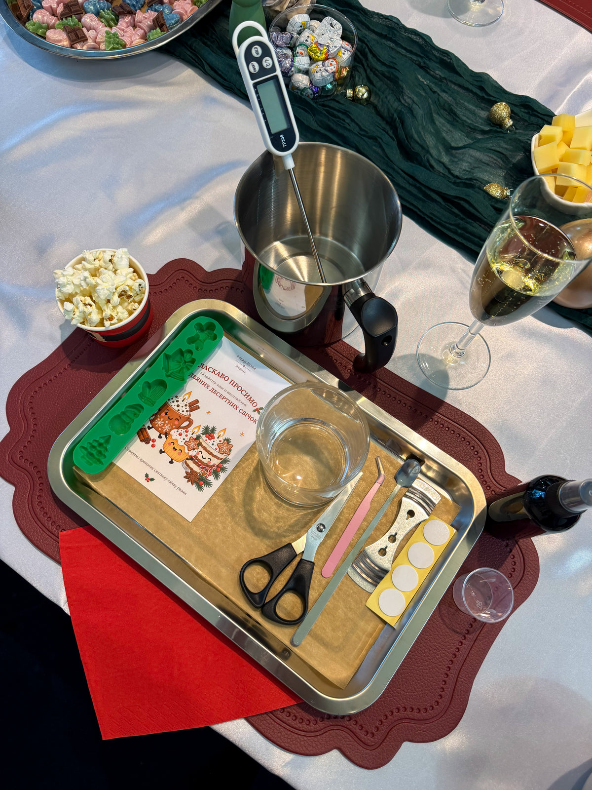 Candle-making station prepared for a Christmas dessert candle workshop in Vienna, with a wax melting pot, thermometer, silicone moulds, decorating tools and festive welcome card.