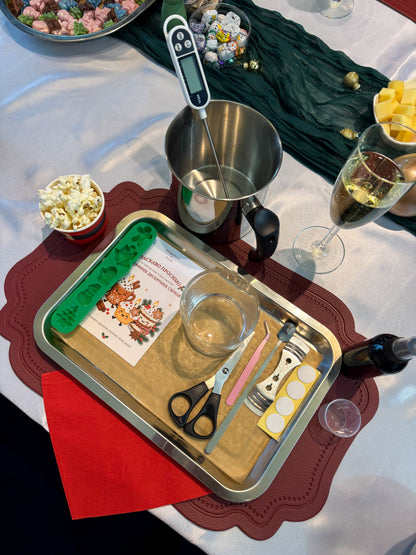 Candle-making station prepared for a Christmas dessert candle workshop in Vienna, with a wax melting pot, thermometer, silicone moulds, decorating tools and festive welcome card.