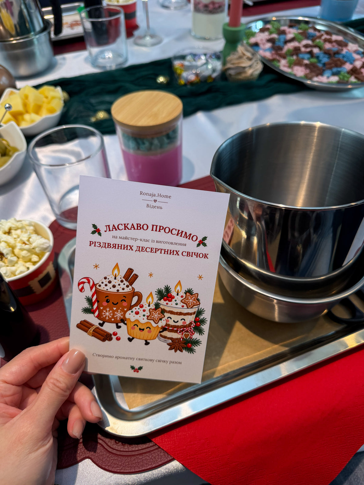 Welcome card in Ukrainian for a Christmas dessert candle-making workshop in Vienna, surrounded by candle-making materials, wax melting equipment and festive decorations.