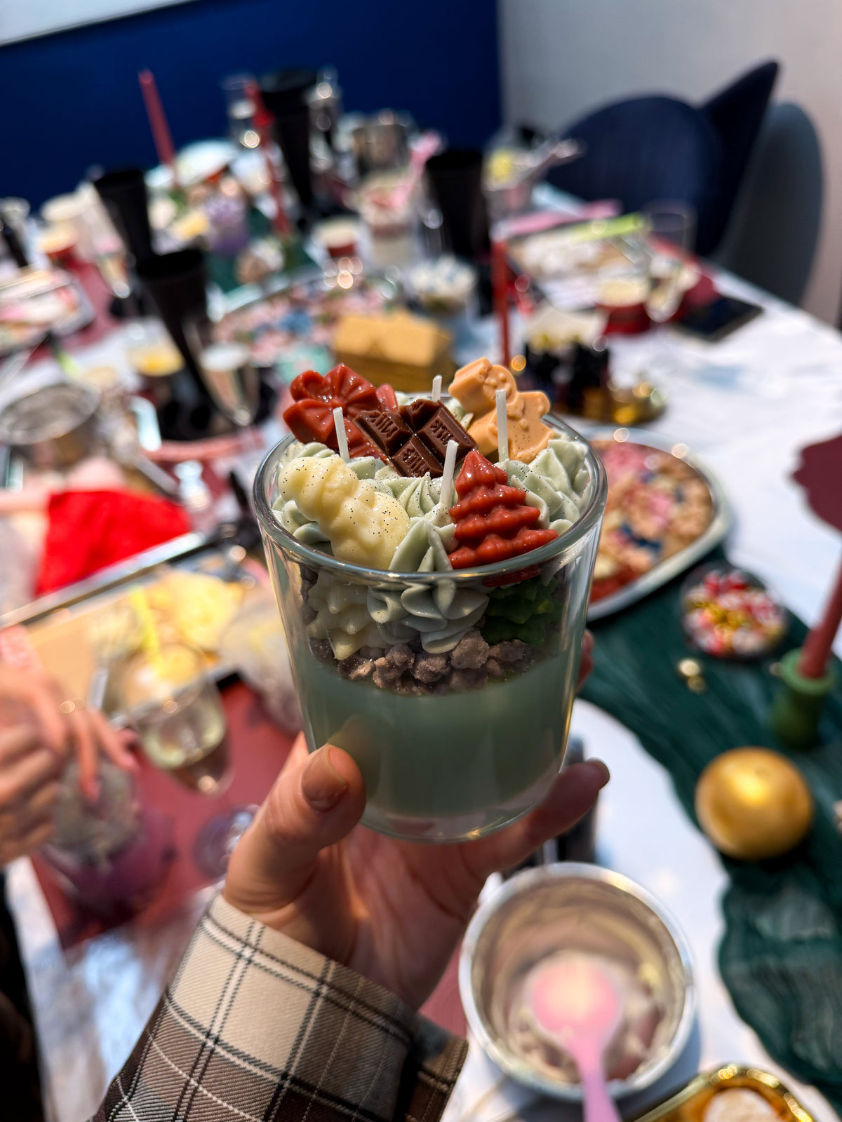 Participant holding a green dessert candle at the workshop table.
