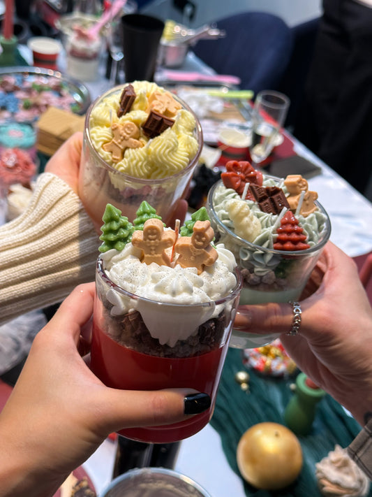 Handmade Christmas dessert candles decorated with whipped wax, gingerbread men and Christmas trees at a candle-making workshop in Vienna.